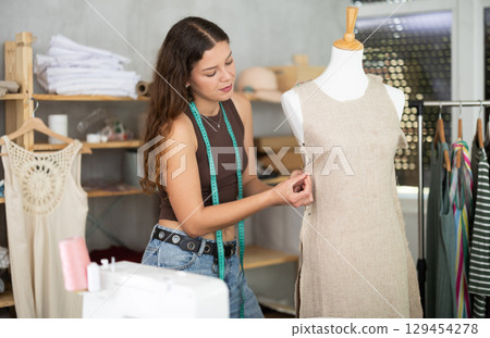 Fashion designer fitting dress on mannequin in dressmaker studio Fashion designer fitting dress on mannequin in dressmaker studio 129454278
