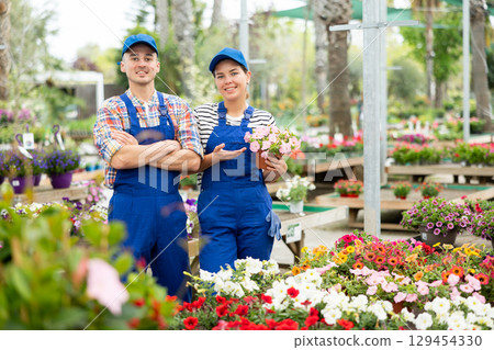 Garden center staff proudly displaying seasonal flowers 129454330