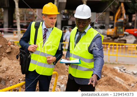 Engineers discussing road mending outdoors Engineers discussing road mending outdoors 129454373