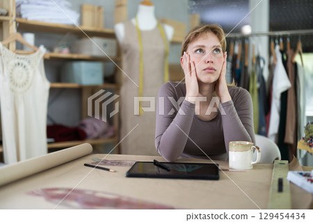 Tired dressmaker worker at table 129454434