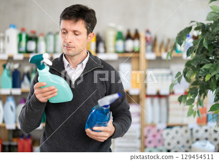Middle-aged man choosing cleaning spray at department store Middle-aged man choosing cleaning spray at department store 129454511