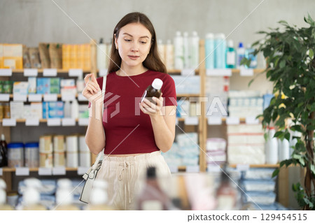 woman chooses a medicinal syrup in a pharmacy woman chooses a medicinal syrup in a pharmacy 129454515