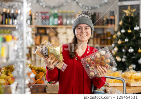 Adolescence girl customer choose consider desserts and sweet snacks. Adolescence girl customer choose consider desserts and sweet snacks. 129454531