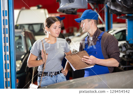 Mechanic guy signs agreement with young woman client 129454542