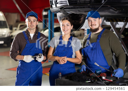 Two positive car mechanics and female worker inviting clients in auto service shop Two positive car mechanics and female worker inviting clients in auto service shop 129454561