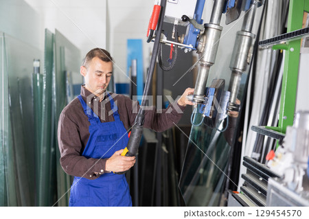 Employee operating glass lifting machine in industrial workshop 129454570
