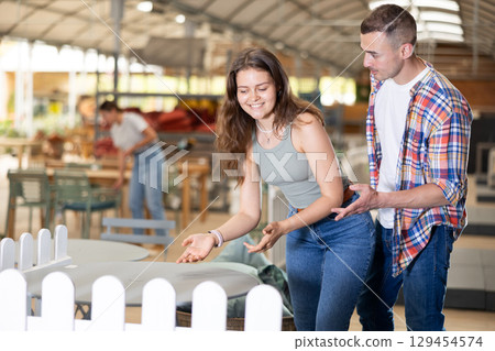 Spouses buyer choose table desk in garden furniture store showroom Spouses buyer choose table desk in garden furniture store showroom 129454574