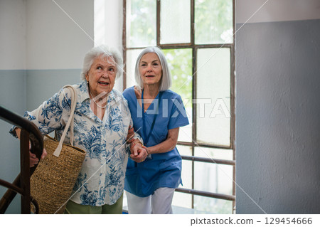 Female healthcare worker helping senior patient walking up the stairs. Female healthcare worker helping senior patient walking up the stairs. 129454666