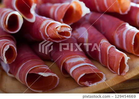 Spanish dry cured jamon on wooden plate Spanish dry cured jamon on wooden plate 129454669