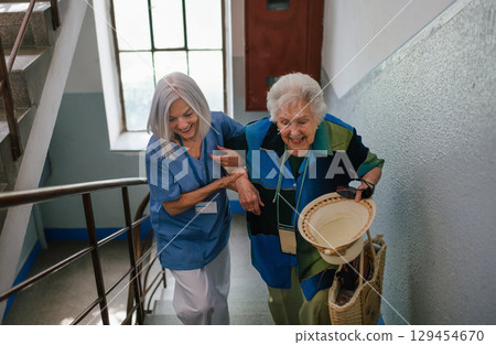 Female healthcare worker helping senior patient walking up the stairs. 129454670