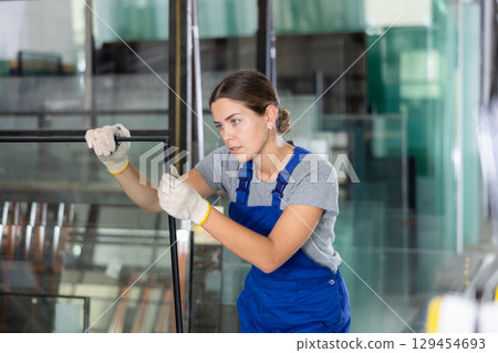 Female worker inspecting insulated glass units in production workshop Female worker inspecting insulated glass units in production workshop 129454693