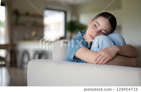 Teenage girl struggling with emotions in living room. Teenage girl struggling with emotions in living room. 129454719
