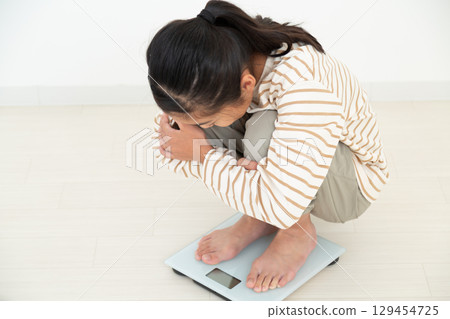 A middle school girl riding a weight scale A middle school girl riding a weight scale 129454725