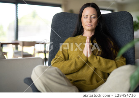 Woman meditating with hands in prayer position 129454736