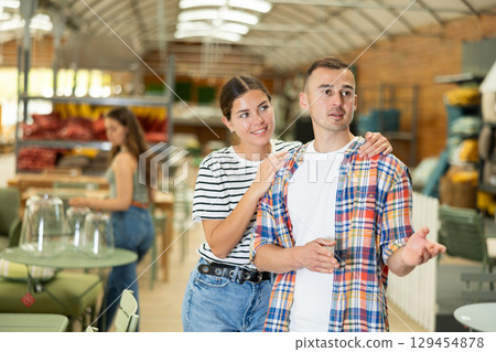 Interested couple looking for functional furniture in garden store 129454878