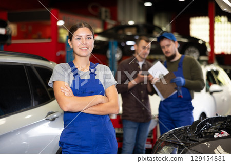 Young female mechanic posing in car service station 129454881