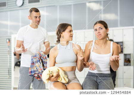 Young man intervenes in conversation between two girls in dressing room. Young man intervenes in conversation between two girls in dressing room. 129454884