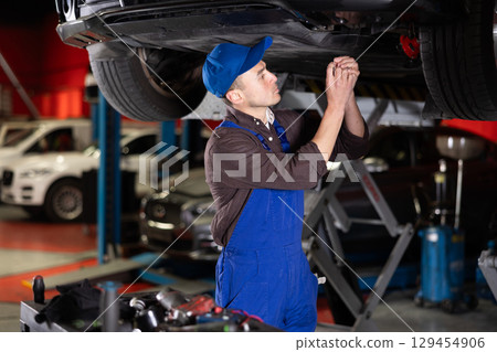 Young mechanic guy fixes car wiring Young mechanic guy fixes car wiring 129454906