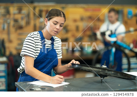 Female bicycle workshop employee making checklist for wheel rim maintenance Female bicycle workshop employee making checklist for wheel rim maintenance 129454978