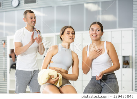 Man and two women talking in locker room 129455045