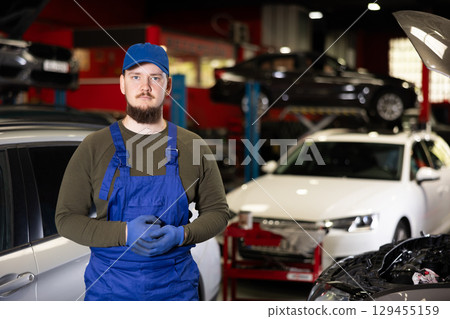 Kind male worker of auto service in blue overalls welcoming clients Kind male worker of auto service in blue overalls welcoming clients 129455159