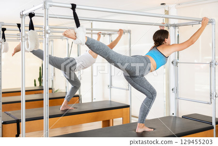 Young woman performing stretching exercises on pilates table Young woman performing stretching exercises on pilates table 129455203