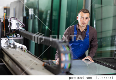 Factory technician processing glass sheet on cutting machine Factory technician processing glass sheet on cutting machine 129455231