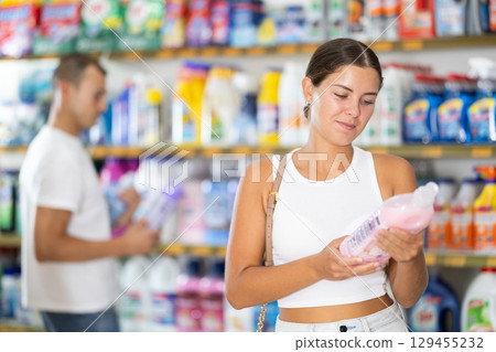 Girl customer in store chooses package of laundry detergent Girl customer in store chooses package of laundry detergent 129455232