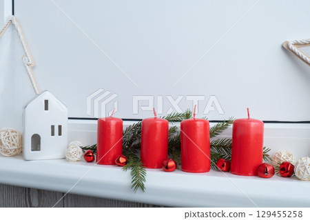 New year and Christmas preparation. Four red advent candles in white windowsill. Handmade eco-friendly decor. Sustainable Christmas decoration New year and Christmas preparation. Four red advent candles in white windowsill. Handmade eco-friendly decor. Sustainable Christmas decoration 129455258