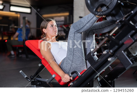 Sporty girl pulls his legs to his chest on special simulator 129455260