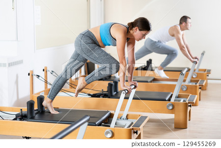 Athletic woman working out with straps in pilates studio 129455269