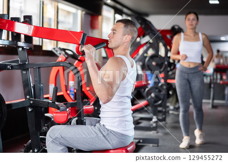 Young man trains his arms on machine 129455272