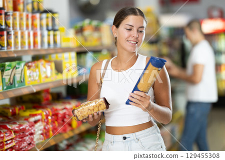 Young woman choosing pasta in store 129455308
