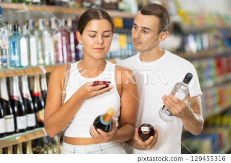 Spouses buyers scan QR code on label of alcohol drinks 129455316
