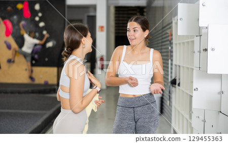 Two young women talking in locker room 129455363