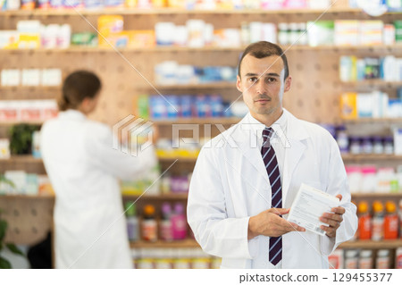 Male consultant pharmacist holds box in hands and offers to purchase remedy to alleviate condition 129455377