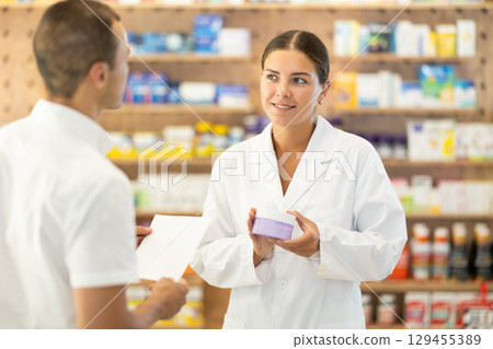 Female pharmacist consulting young guy about cosmetic cream 129455389