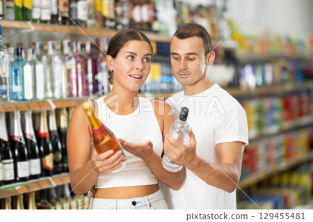 Married couple chooses alcoholic drinks in supermarket - vodka, champagne or whiskey Married couple chooses alcoholic drinks in supermarket - vodka, champagne or whiskey 129455481