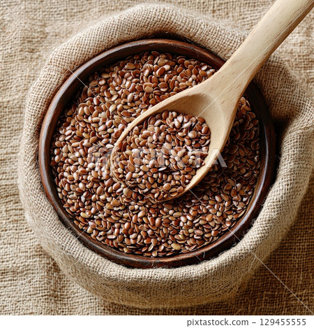 Flaxseed bowl with wooden spoon on natural textured background 129455555