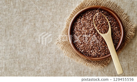 Minimalist bowl with flaxseed and spoon on beige backdrop 129455556