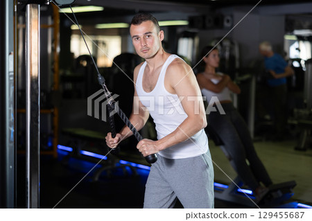 Man in sportswear training on rope loop simulator 129455687