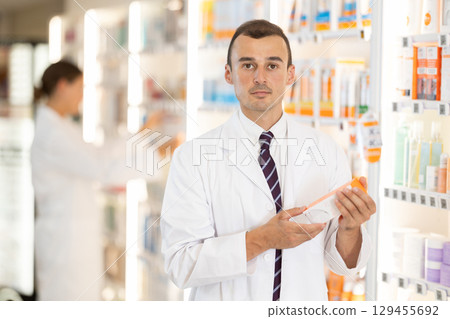 Young male pharmacist offering preparation in box 129455692