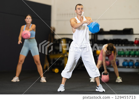 Young man training with kettlebell in gym Young man training with kettlebell in gym 129455713