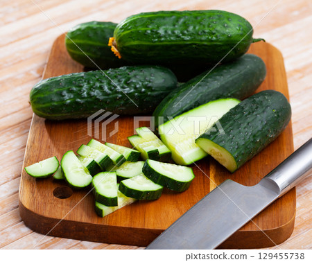 Ripe green cut cucumbers on wooden background Ripe green cut cucumbers on wooden background 129455738