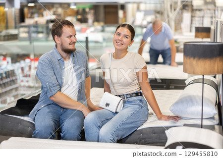 Married couple chooses a mattress on bed together in store 129455810