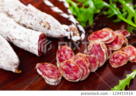 Chopped sausage fuet on wooden table Chopped sausage fuet on wooden table 129455919