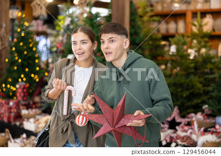 Young married couple chooses New Year toys and decorations in store or market 129456044