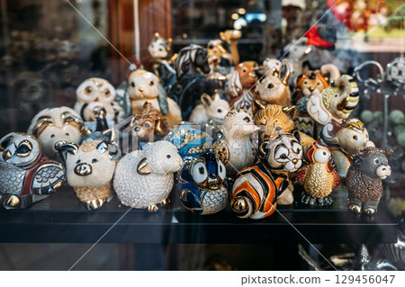 Colorful ceramic animal figurines are displayed behind glass in a storefront window. Collectibles market, nostalgia design, memory-based marketing, curated collections 129456047