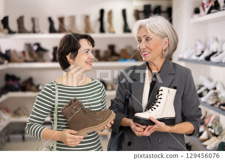 Adult and elderly women choosing boots in store 129456076