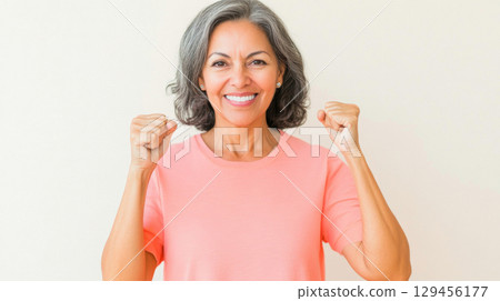 Middle aged latin american woman with raised fist of empowerment, strength and women solidarity, International Womens Day concept 129456177